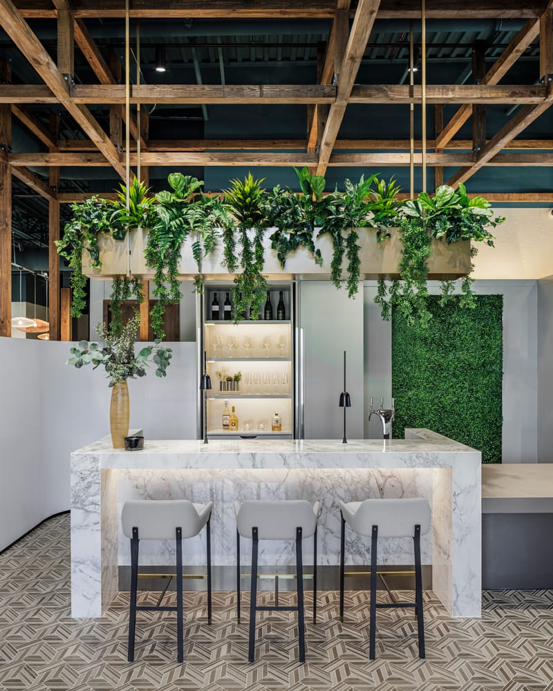 Marble bar with waterfall edges, illuminated back bar, and suspended greenery